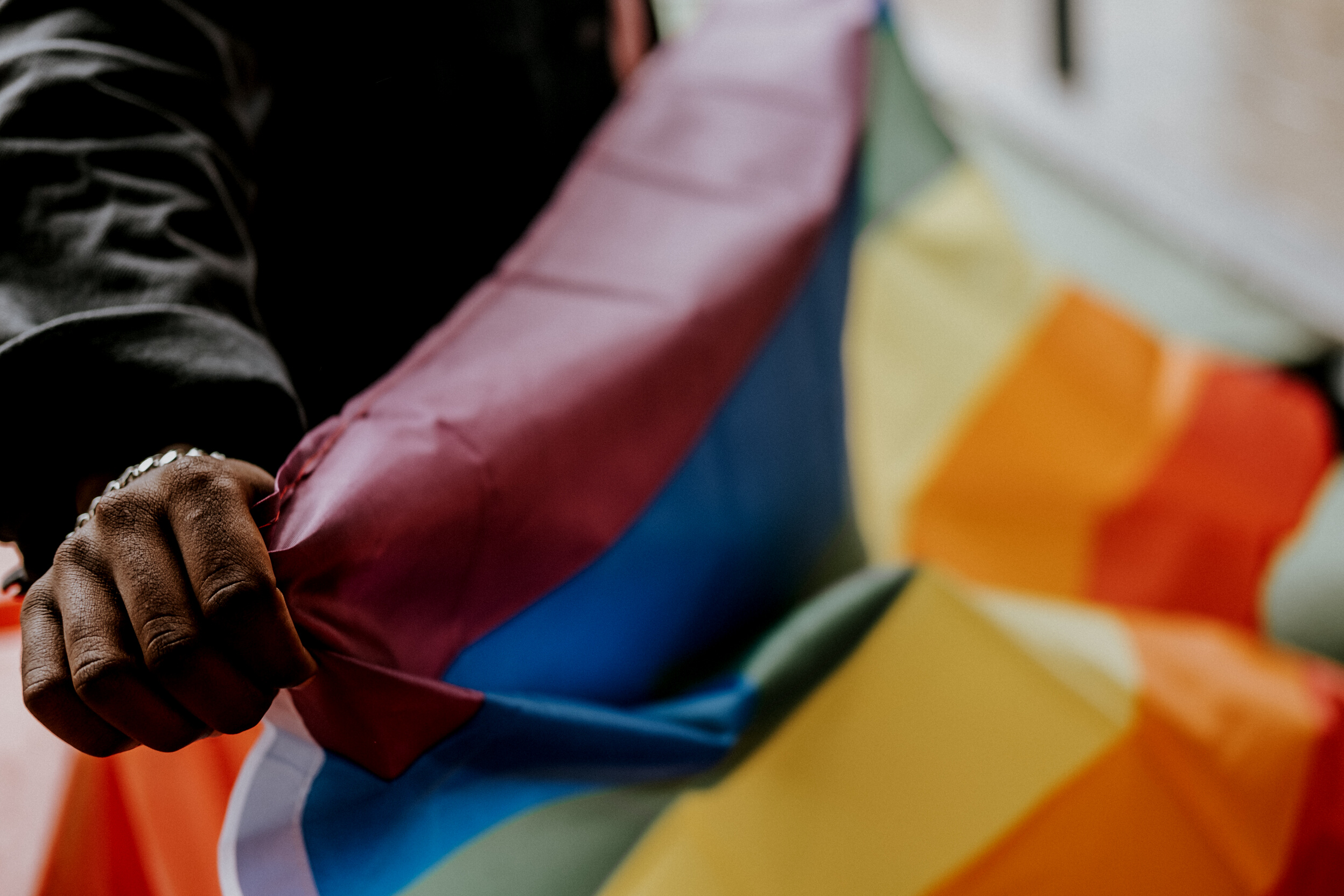 Crop unrecognizable black gay demonstrating LGBT flag
